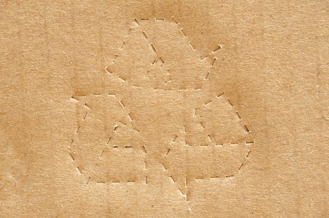 Perforated stamped recycling icon on a brown cardboard box or pacing carton on a close up full frame view in an environmental concept