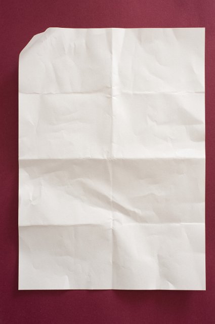 a folded sheet of A4 paper on burgundy background