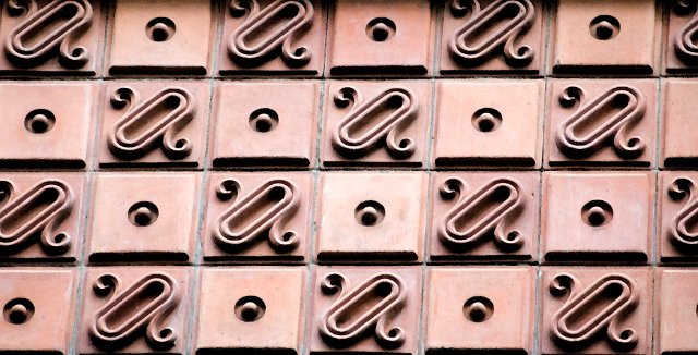 pattern of decorative tiles on an old building facade
